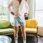 Man wearing a white shirt and dog house slim fit boxers in a living room.