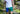 Close up of a man in forest wearing white t-shirt and blue/green/yellow multi colored mesh lounge shorts.