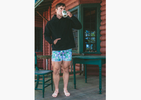 Man standing drinking coffee and wearing black hoodie and green madras slim fit boxer