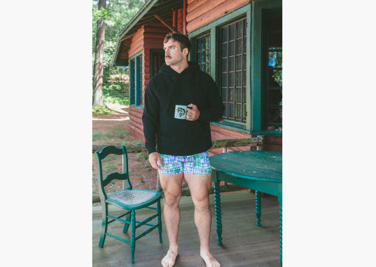 Man standing wearing black hoodie and green madras slim fit boxer