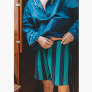 Close up shot of man on boat wearing green/navy lounge shorts and blue jacket