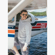 Man wearing grey hoodie standing on dock getting into a small plane 