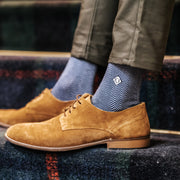 Herringbone monogrammed socks worn with brown shoes on stairs.
