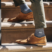 Man on steps in brown dress shoes and monogram pyramids socks.