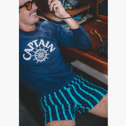 Man sitting on boat holding radio wearing navy sweatshirt and navy stripe slim fit boxers.