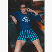 Man sitting on boat holding radio wearing navy sweatshirt and navy stripe slim fit boxers.