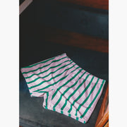 Pair of pink/green stripe slim fit boxers laid flat on the seat of a boat.