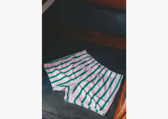 Pair of pink/green stripe slim fit boxers laid flat on the seat of a boat.