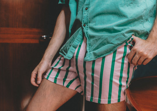 Close up shot of man wearing green shirt and green/pink stripe slim fit boxers.