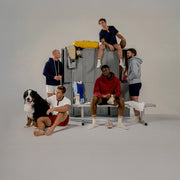 Group of people and a dog in a casual setting with lockers and sports equipment wearing various nice laundry t shirts, hoodies, and lounge shorts.