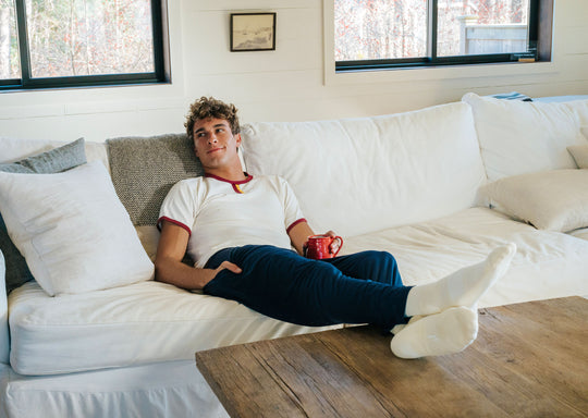 Man laying on couch wearing white tshirt and navy blue lounge pants. 