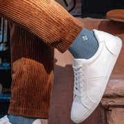 Man wearing herringbone monogram socks on townhouse steps.