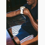 Close up of man drinking coffee wearing a blue shirt and red/white/blue Regatta stripe slim fit boxer.
