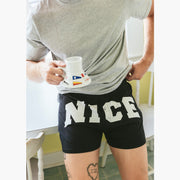 Close up of man in kitchen holding coffee mug and wearing a pair of black slim fit boxers with the words "NICE" in big bold white font.