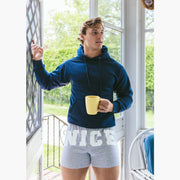 Man standing inside of house wearing navy blue sweatshirt and grey slim fit boxers with words "NICE" on the front in white bold font.