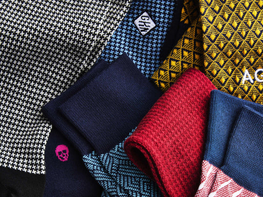 Macro detail texture shot of various monogrammed dress socks in cubes, houndstooth and tile patterns.