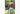 Back shot of shirtless man standing at archery range holding a box wearing white mesh shorts.