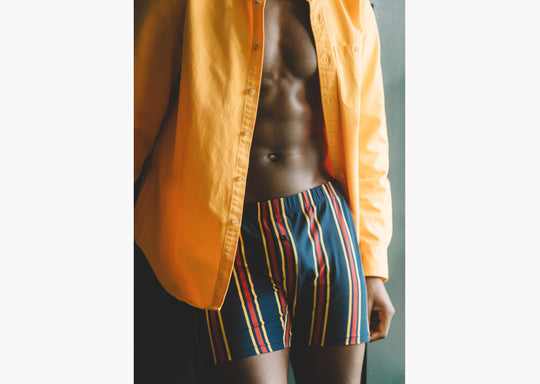 Man wearing yellow/red/blue stripe slim fit boxers and an open yellow dress shirt.