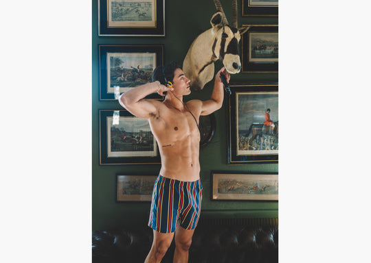 Shirtless man wearing yellow/red/blue stripe slim fit boxers and an open yellow dress shirt.