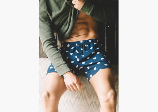 Man lifting shirt to show abs wearing blue slim fit boxers with white dots.