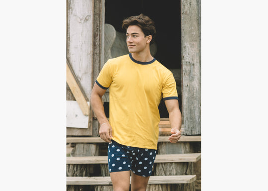 Man wearing yellow shirt and blue slim fit boxers with white dots.