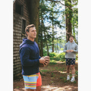 Man holding football wearing navy hoodie in forest
