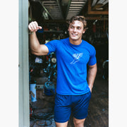 Man standing in garage wearing blue shirt and blue lounge shorts.