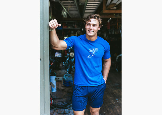 Man standing in garage wearing blue shirt and blue lounge shorts.