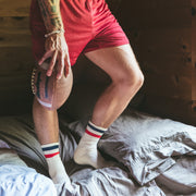 Man holding football on a bed in tech varsity socks.