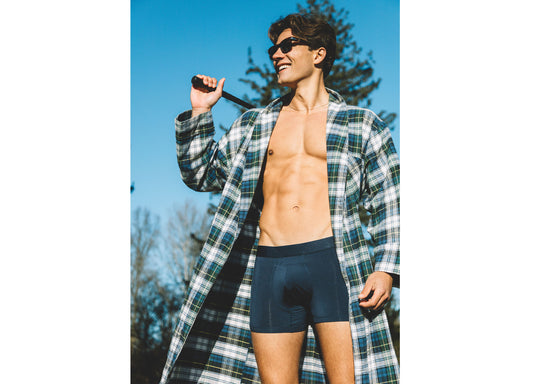 Shirtless man wearing open robe and blue boxer briefs holding a golf club on his shoulder.