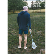 Back shot of man standing in grass field wearing a black hoodie.