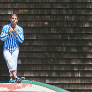 Man standing by building roof wearing blue and white stripe cabana hoodie. 