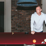 Man standing by pool table wearing linen stripe hoodie.