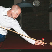 Man playing pool wearing linen stripe hoodie.