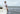 Man sitting by edge of boat with feet over water wearing linen stripe hoodie.