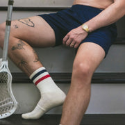 Man sitting on staircase wearing navy blue lounge short and tech varsity crew socks