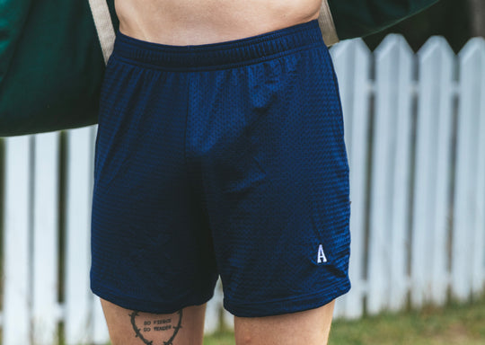 Man standing in front of fence wearing navy blue lounge short with letter "A" monogram