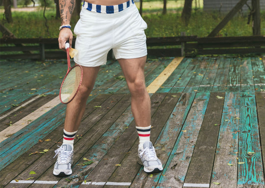 Man in tech varsity socks and cream lounge shorts on court.