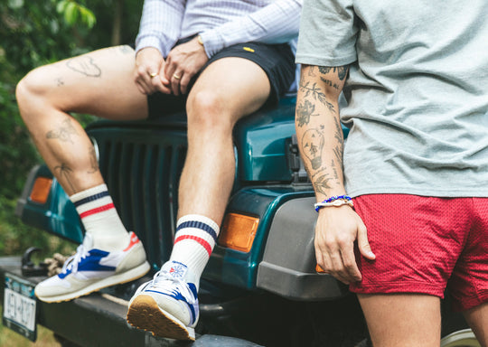 Two men on Jeep wearing tech varsity socks and lounge shorts.