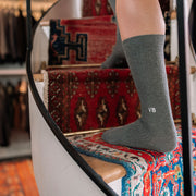 Close up of man walking up spiral staircase wearing grey ribbed dress sock with VB initials monogrammed on one. 