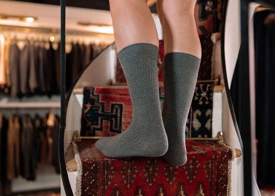 Man walking up spiral staircase wearing grey ribbed dress socks.