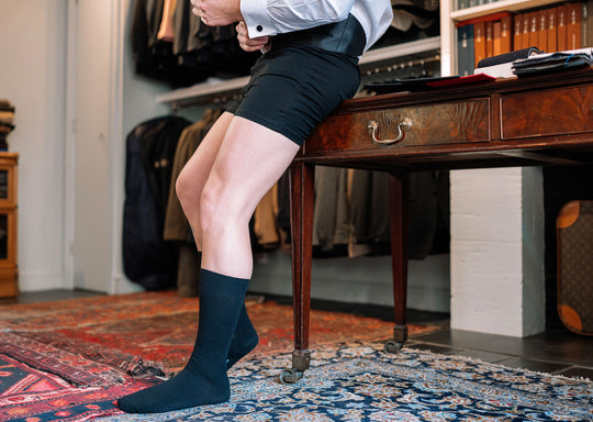Man getting dressed in a suit wearing black slim fit boxers and black ribbed dress socks.