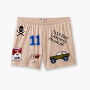 Beige lounge short that says "cash rules everything around me" with various icons like 11 patch, truck, football, skull and bones etc. flat on grey background.
