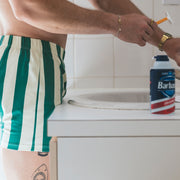 Man wearing hunter green and cream stripe slim fit boxer in bathroom shaving.