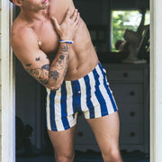 Man wearing blue and cream stripe slim fit boxer standing shirtless in a doorway.
