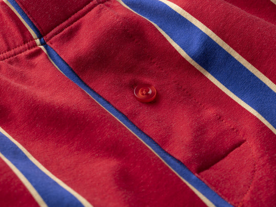 Close up detail shot of red/blue/yellow stripe slim fit boxer with red button.