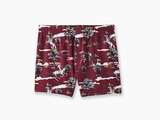 Pair of red slim fit boxers with trees and men riding horses printed on sitting against light grey background.
