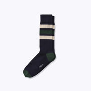 A dress sock with white, blue, and hunter stripes laid flat on light grey background.