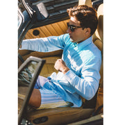Man sitting in convertible car wearing blue dress shirt and pastel stripe slim fit boxers. 
