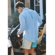 Man standing in front of open door by car wearing blue dress shirt and pastel stripe slim fix boxers.